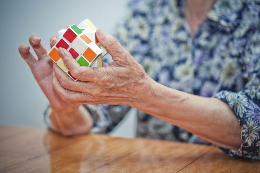 Idosa resolvendo um cubo mágico, auxiliando no tratamento da doença de Parkinsons