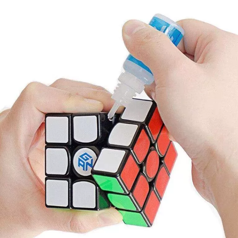 Imagem de uma mão segurando um cubo mágico e outra lubrificando o brinquedo 