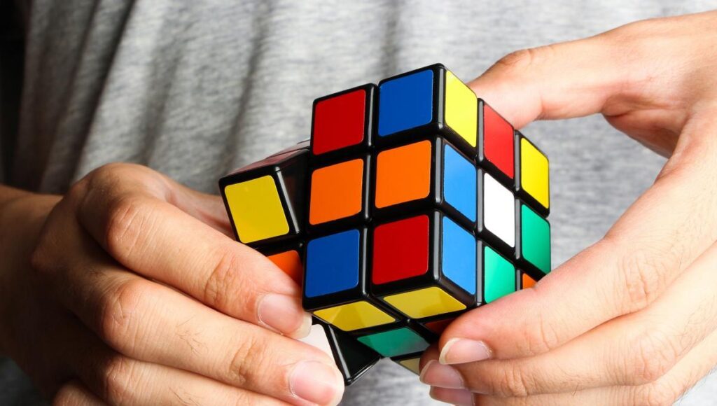 Imagem de uma mão segurando um cubo 3x3x3, para ilustrar os campeonatos de cubo mágico do mês de outubro de 2023